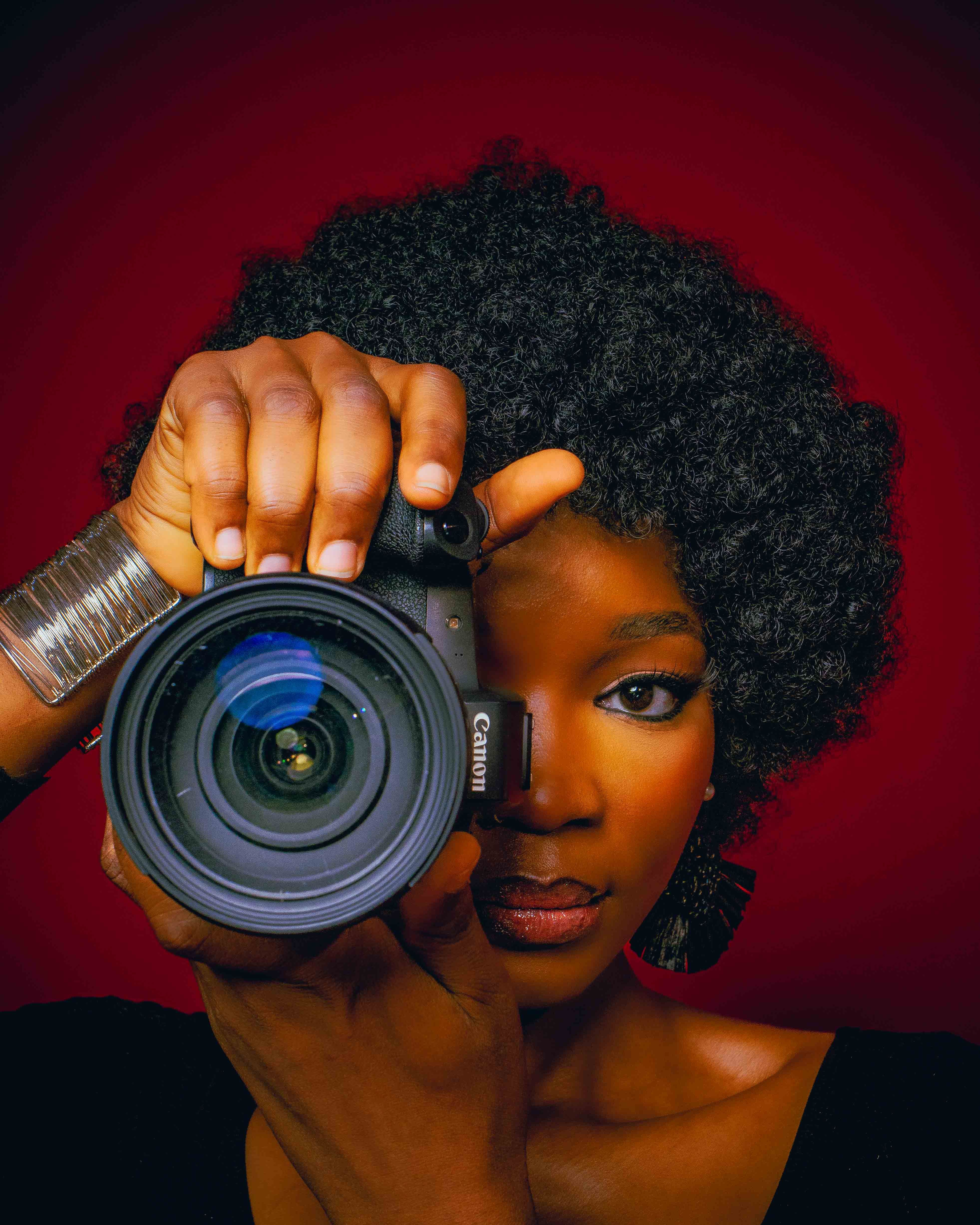 Woman photographer looking through a camera in a warmly lit studio