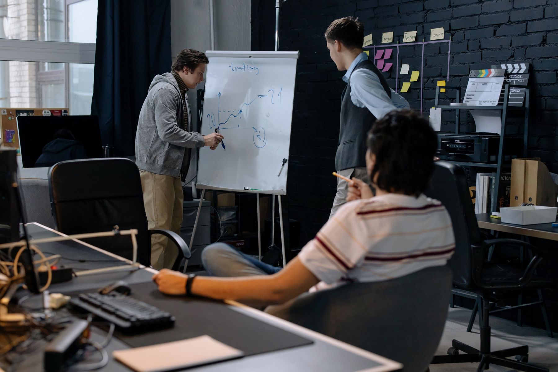 Production team planning a project around a meeting table and whiteboard